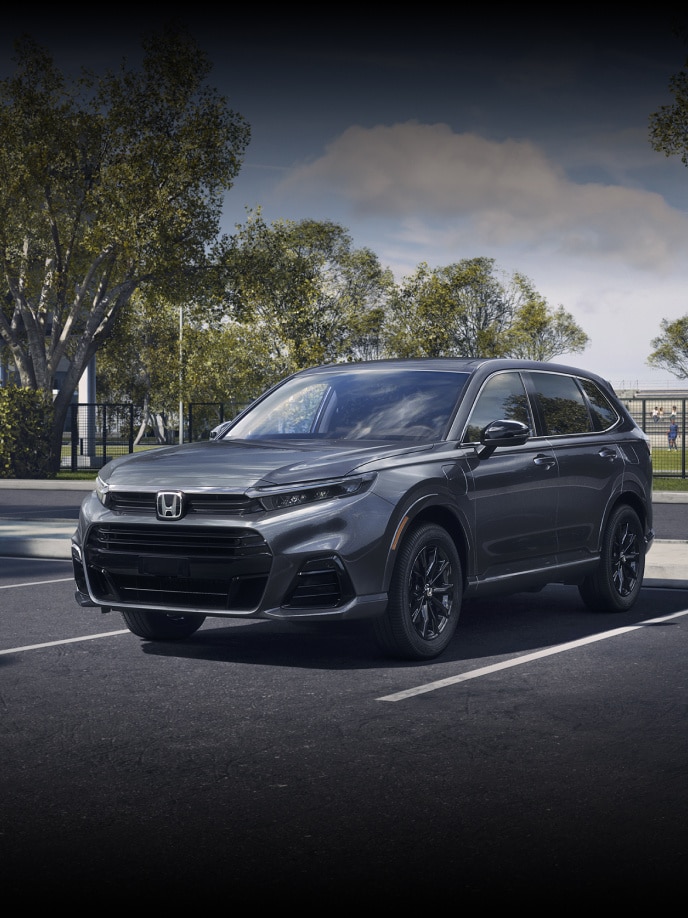 Front driver of 2026 CR-V e:FCEV in Meteorite Gray Metallic parked in a sports complex parking lot.
