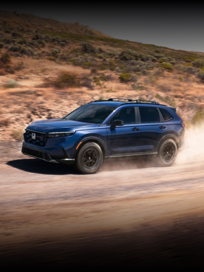 2026 Honda CR-V TrailSport in Canyon River Blue Metallic, front driver action shot of vehicle driving on a dirt road.