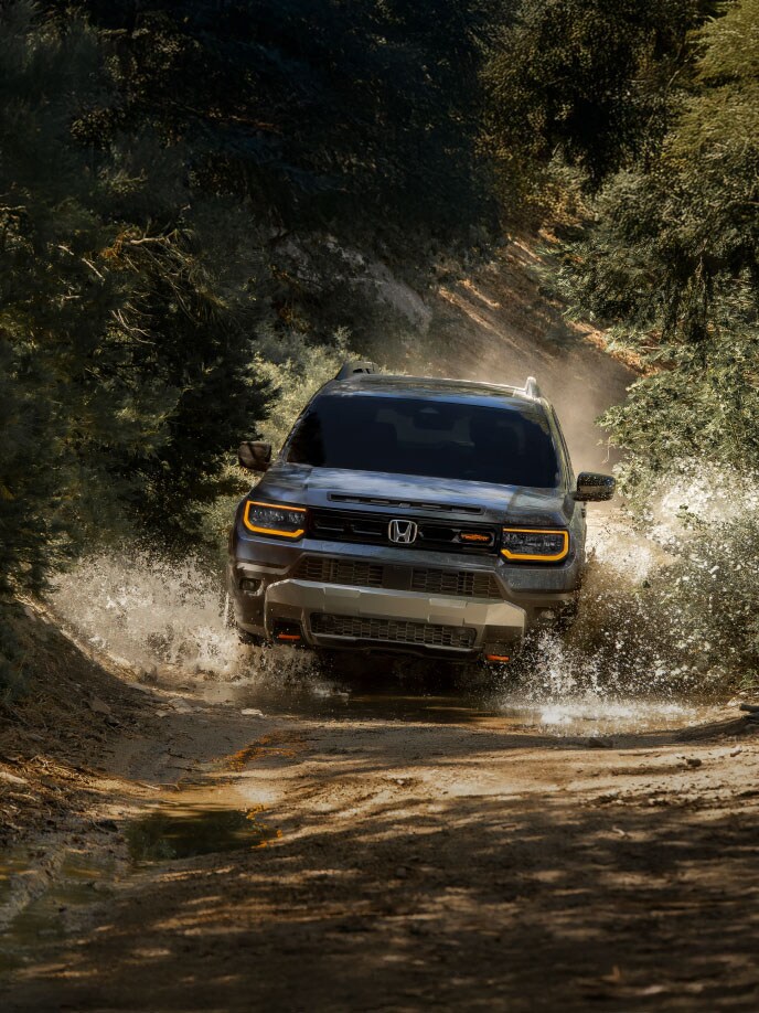2027 Honda Passport TrailSport Elite in Smoke Blue Pearl in a front view, driving through water on an off-road trail (Mid-Size SUV).