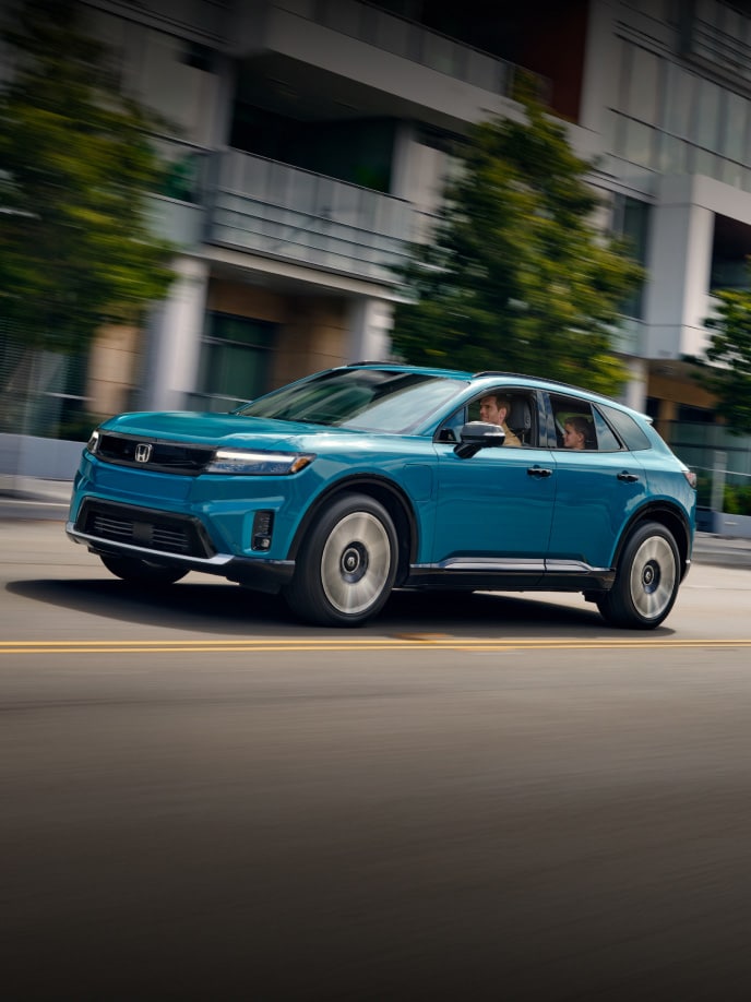 2026 Honda Prologue Elite in North Shore Pearl, driving down a city street.