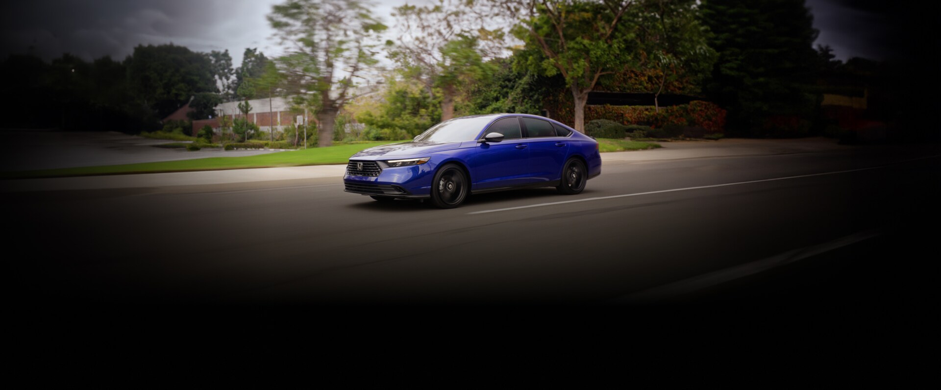 2026 Honda Accord Sport L Hybrid in still night pearl front driving on a road with blurred trees (Mid-Size Sedan).