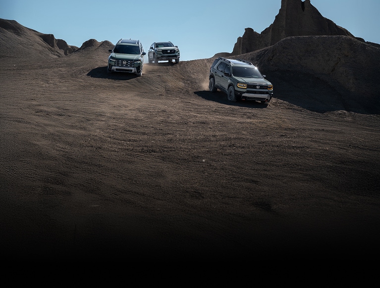 2026 Honda Pilot TrailSport, CR-V TrailSport, and Passport TrailSport in Ash Green Metallic front driving off-road.