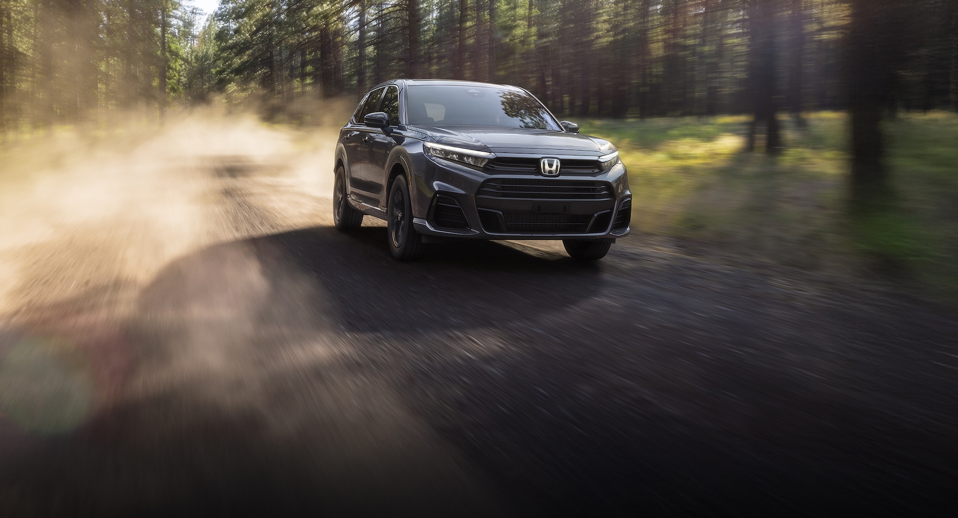 Front driver action shot of 2026 CR-V e:FCEV in Meteorite Gray Metallic driving on a forest.