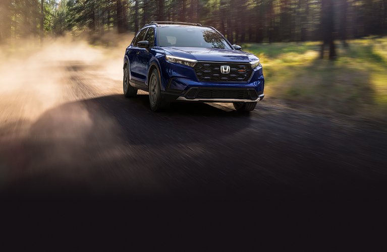 2026 Honda CR-V TrailSport Hybrid in Canyon River Blue Metallic driving in a offroad path 2026 Honda CR-V TrailSport Hybrid in Canyon River Blue Metallic driving in a offroad path