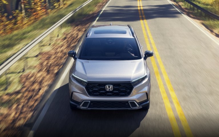 2026 Honda CR-V Sport Touring front view of vehicle driving on a curved road crossing a lake.