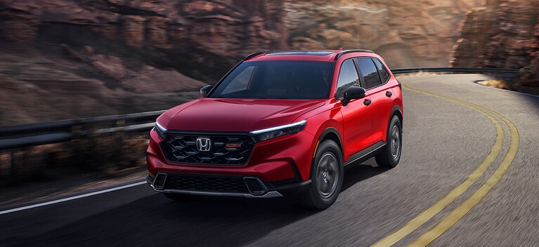 2026 Honda CR-V TrailSport Hybrid in Radiant Red Metallic front view driving on a canyon road (Compact Crossover SUV).