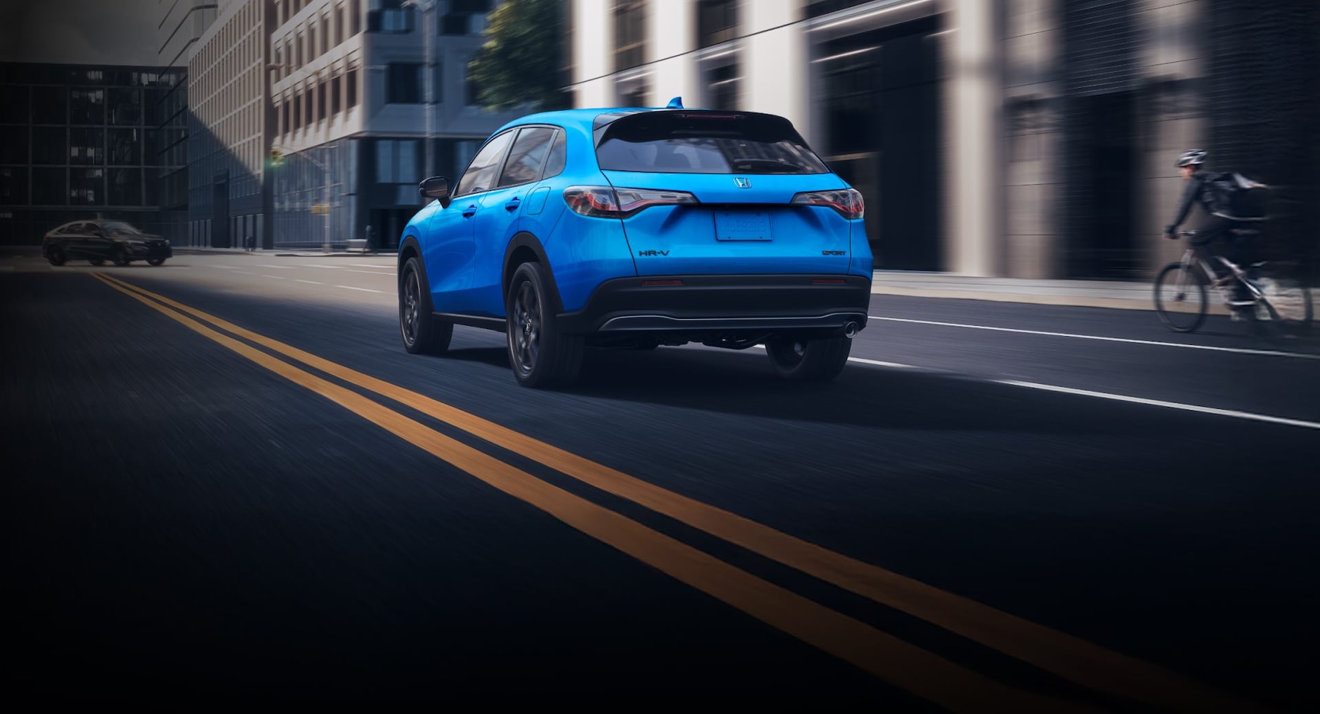 2026 Honda HR-V in Boost Blue Pearl driving in the city, rear view
