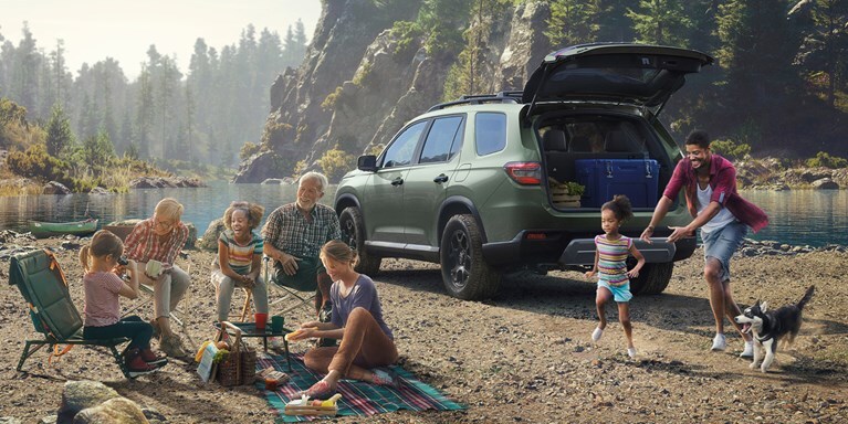 2026 Honda Pilot TrailSport shown in Ash Green Metallic with Honda Genuine Accessories in the lake