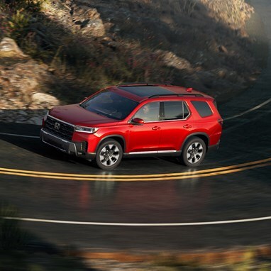 2026 Honda Pilot Elite shown in Radiant Red Metallic II on the road