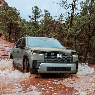 2026 Honda Pilot TrailSport shown in Ash Green Metallic crossing the river