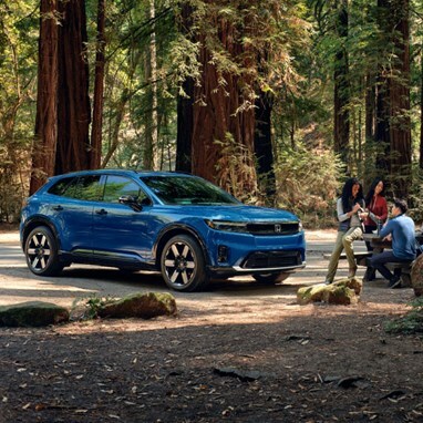 2026 Honda Prologue Elite in Pacific Blue Metallic, parked in a redwood forest, with people enjoying a picnic lunch.