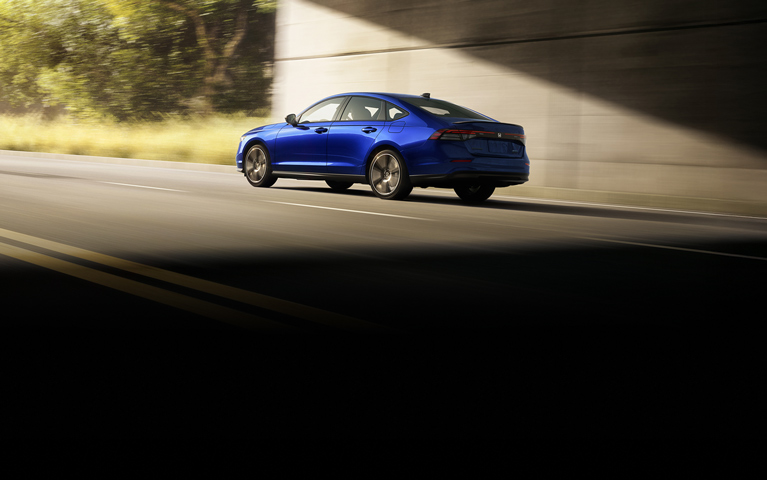 2026 Honda Accord Sport Hybrid in Still Night Pearl driving in an urban environment. 2026 Honda Accord Sport Hybrid in Still Night Pearl driving in an urban environment.