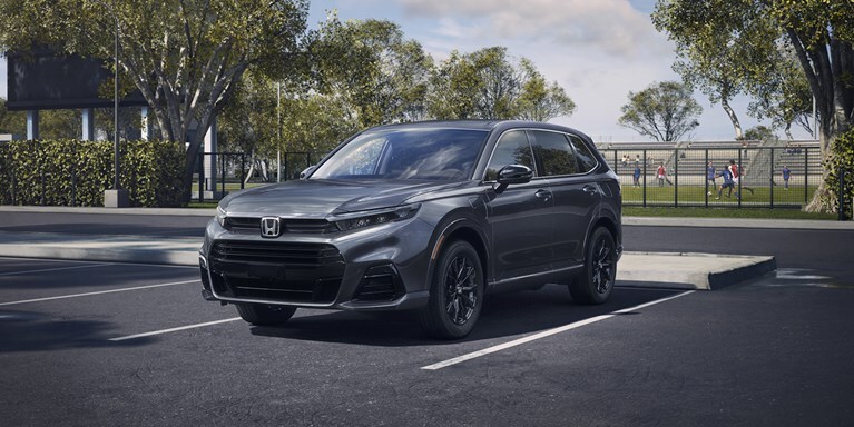 Front driver of 2026 CR-V e:FCEV in Meteorite Gray Metallic parked in a sports complex parking lot.