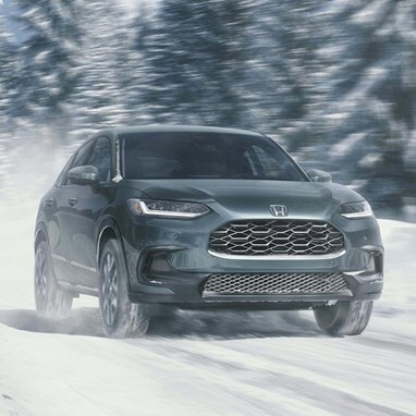 2027 Honda HR-V EX-L in Nordic Forest Pearl front view driving on a snowy road (Subcompact Crossover SUV).