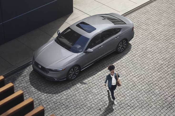 2026 Honda Accord in Urban Gray Pearl top cobblestone street with a pedestrian walking (Mid-Size Sedan).