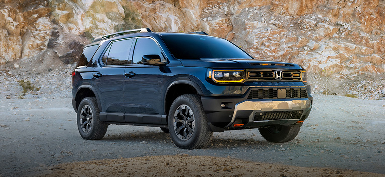 2027 Honda Passport TrailSport Elite in Smoke Blue Pearl in a three-quarter view, parked in a rugged rocky quarry environment (Mid-Size SUV).