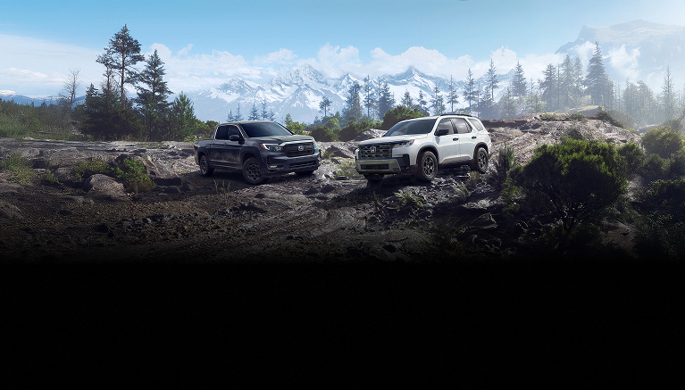 2026 Honda Ridgeline TrailSport in Modern Steel Metallic (Midsize Pickup Truck) and 2026 Honda Pilot TrailSport in Platinum White Pearl (Full-Size SUV), both with Honda Genuine Accessories, shown in a three-quarter view and parked in a rugged rocky quarry environment.
